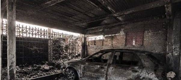 El garage con un auto calcinado en el centro. Las paredes y el techo de chapa están negros y el piso está cubierto de restos quemados.